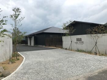 유후 릿카 콘크리트 담장에 '由布院 六花' 간판이 걸린 진입로와 검은 목조 건물