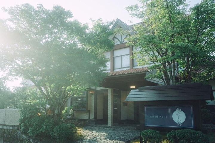 유후인 료칸 히카리노이에 나무 사이로 보이는 서양풍 건물과 「Hikari No Ie」 간판